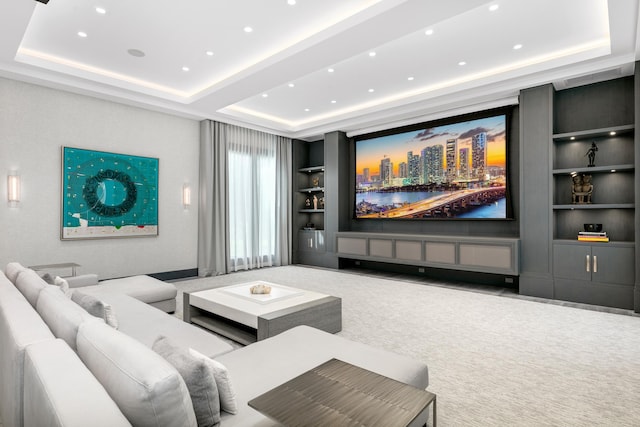 cinema room with a tray ceiling, built in features, and carpet