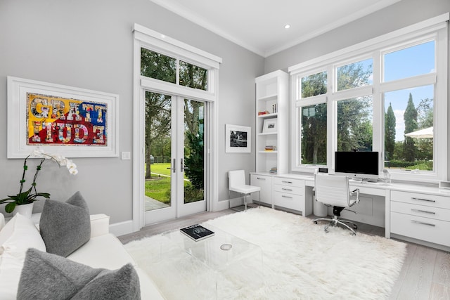 home office featuring ornamental molding, built in desk, light wood-type flooring, and french doors