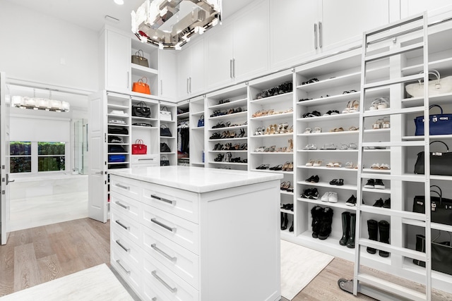 spacious closet with a chandelier and light hardwood / wood-style floors