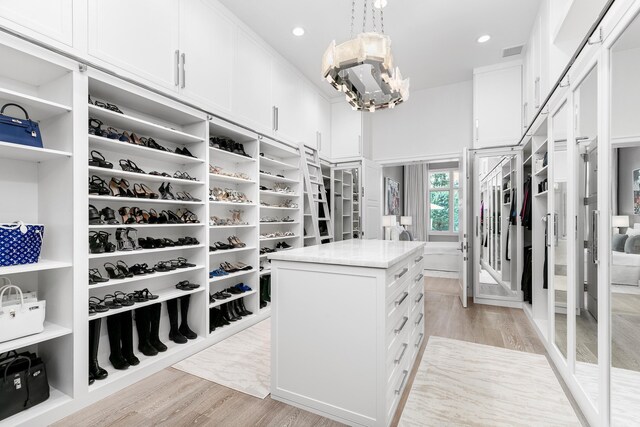 walk in closet featuring an inviting chandelier and light wood-type flooring