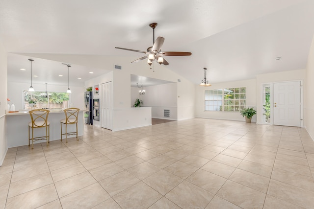 living room featuring ceiling fan with notable chandelier, lofted ceiling, and light tile patterned floors