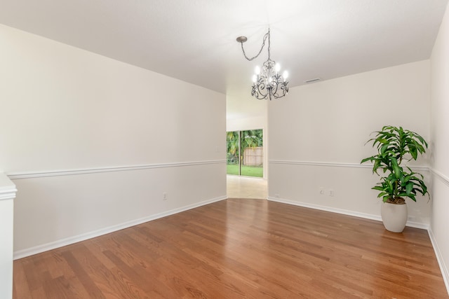 unfurnished room featuring an inviting chandelier and hardwood / wood-style floors