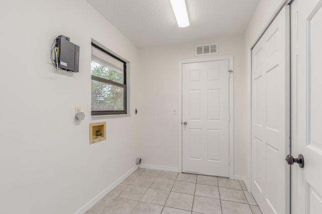 laundry area with washer hookup, a textured ceiling, and light tile patterned floors