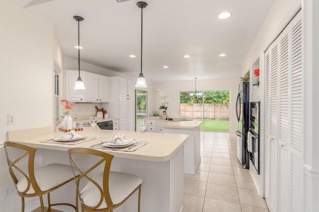 kitchen featuring a kitchen breakfast bar, black appliances, hanging light fixtures, kitchen peninsula, and white cabinets