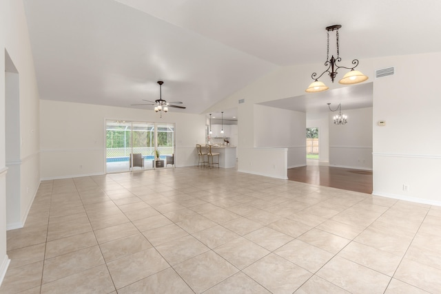 unfurnished living room featuring ceiling fan with notable chandelier, vaulted ceiling, and light tile patterned floors