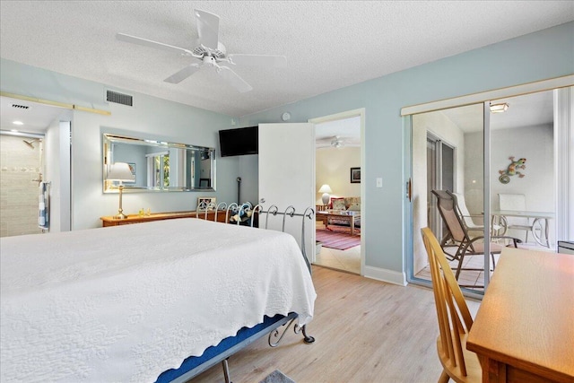 bedroom featuring a ceiling fan, baseboards, visible vents, light wood-style flooring, and a textured ceiling