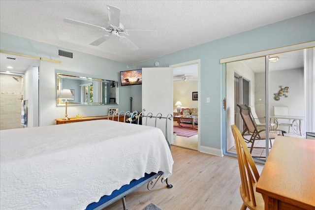 bedroom featuring visible vents, a textured ceiling, light wood-style flooring, and a ceiling fan