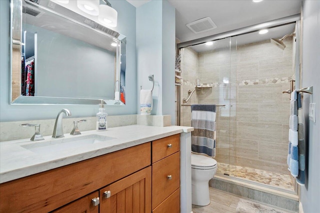 bathroom with visible vents, a shower stall, vanity, and toilet