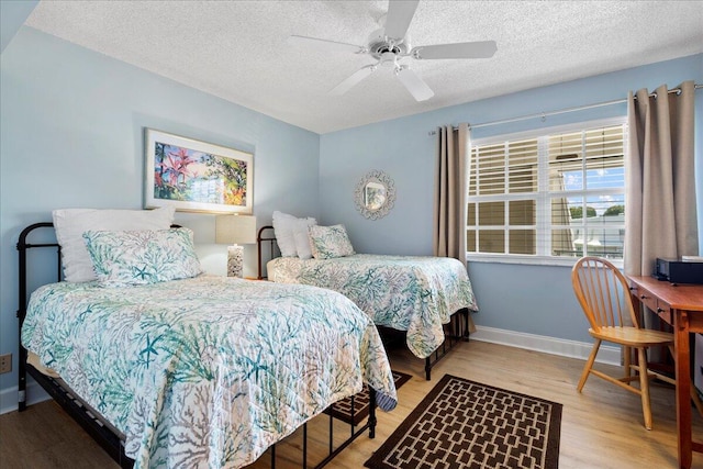 bedroom featuring a textured ceiling, a ceiling fan, baseboards, and wood finished floors
