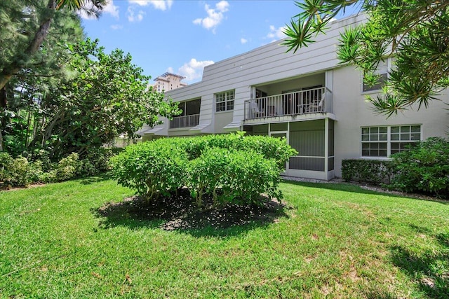 rear view of house with a balcony and a lawn