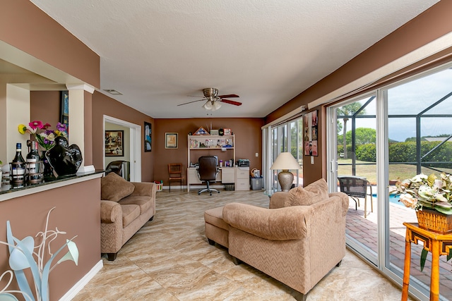 living room featuring ceiling fan and a textured ceiling