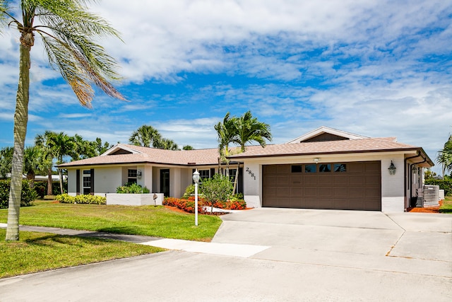 single story home featuring central air condition unit, a garage, and a front lawn