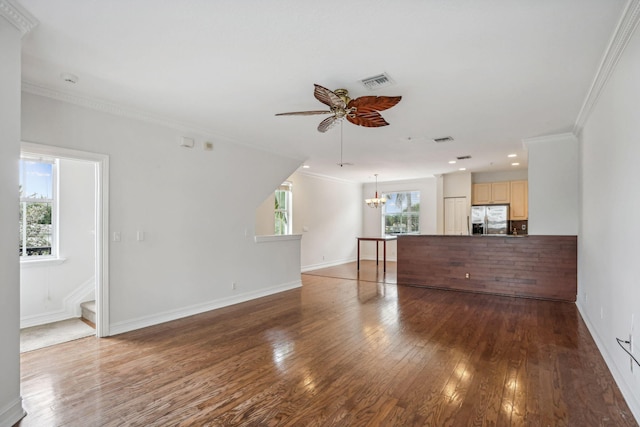 unfurnished living room featuring ceiling fan with notable chandelier, dark hardwood / wood-style floors, plenty of natural light, and crown molding