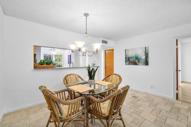 dining area with a textured ceiling, an inviting chandelier, and sink