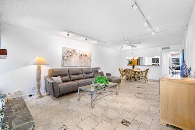 living room with a textured ceiling, ceiling fan, and track lighting