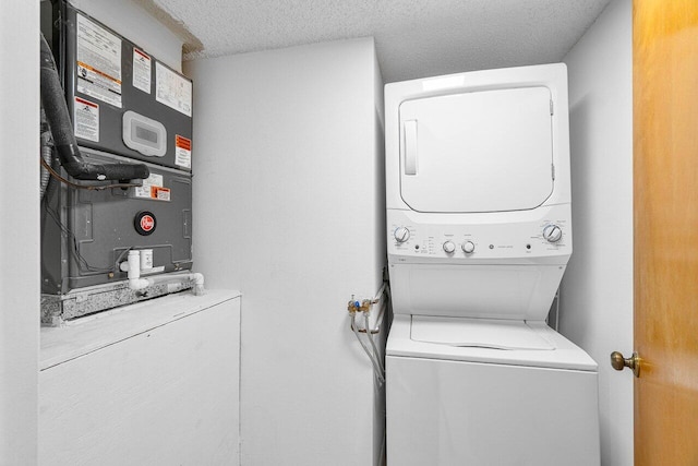 clothes washing area featuring stacked washer and clothes dryer and a textured ceiling