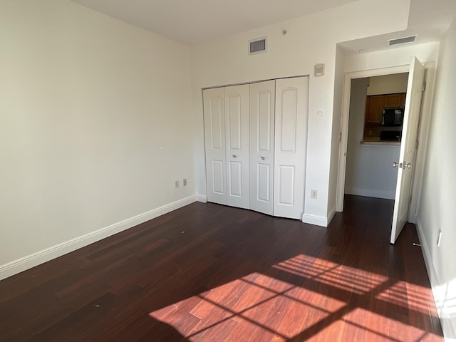 unfurnished bedroom featuring dark hardwood / wood-style flooring and a closet