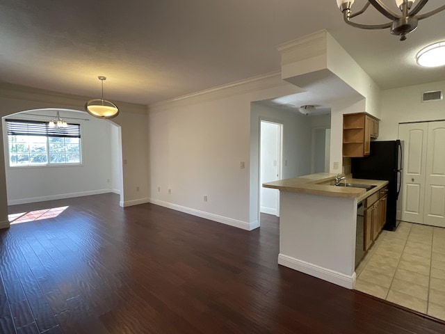 kitchen featuring an inviting chandelier, ornamental molding, light hardwood / wood-style floors, kitchen peninsula, and hanging light fixtures