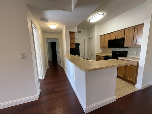 kitchen featuring kitchen peninsula, light hardwood / wood-style flooring, black appliances, decorative backsplash, and sink