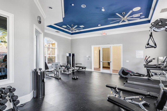 workout area featuring a raised ceiling and crown molding