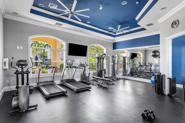 workout area featuring a raised ceiling, ceiling fan, and crown molding