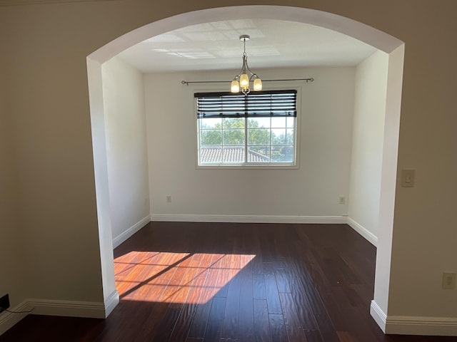 unfurnished room with an inviting chandelier and dark hardwood / wood-style floors