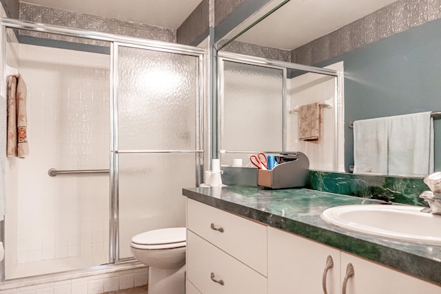 bathroom featuring vanity, an enclosed shower, and toilet