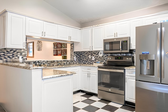 kitchen with white cabinetry, vaulted ceiling, appliances with stainless steel finishes, light stone countertops, and backsplash