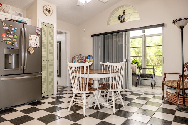 dining space featuring ceiling fan, lofted ceiling, and a textured ceiling