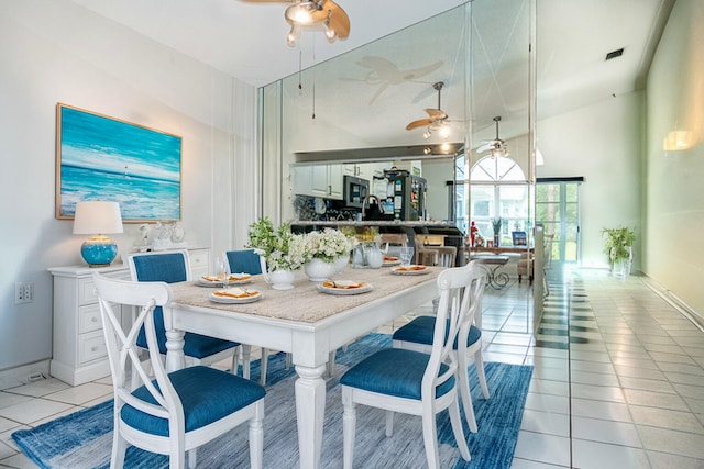 tiled dining room with ceiling fan and a high ceiling