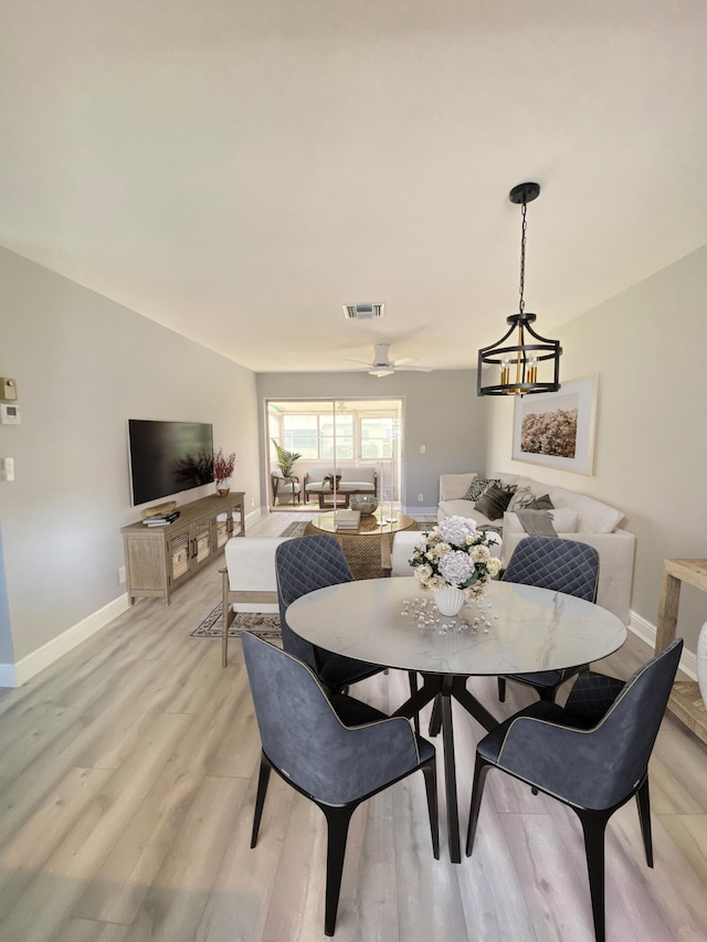 dining area with ceiling fan with notable chandelier and light wood-type flooring