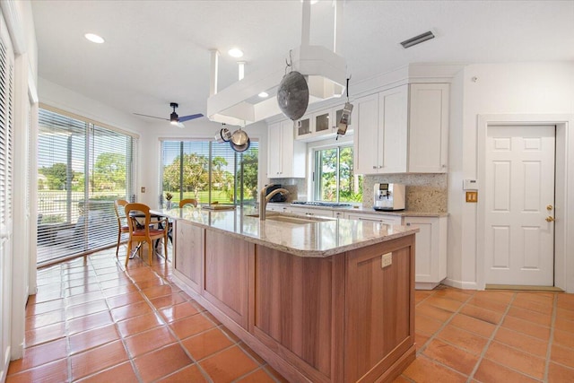 kitchen featuring white cabinetry, tasteful backsplash, sink, and a center island with sink