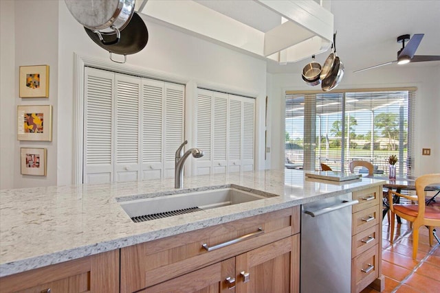 kitchen with sink, stainless steel dishwasher, and light stone countertops