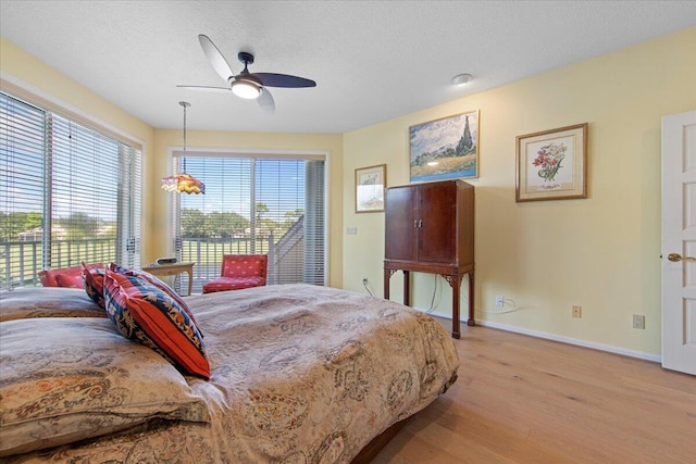 bedroom featuring ceiling fan, access to exterior, a textured ceiling, and light wood-type flooring