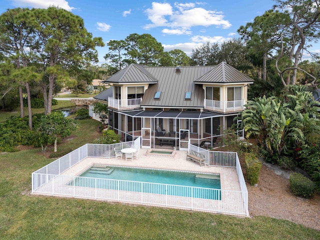 back of house with a balcony, a yard, a patio area, and a sunroom