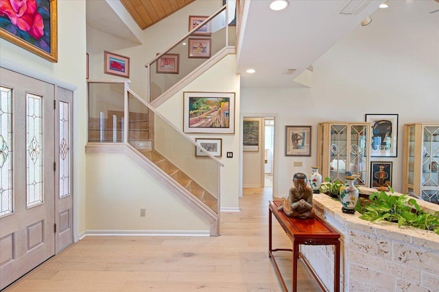 foyer entrance featuring wood ceiling, high vaulted ceiling, and light wood-type flooring