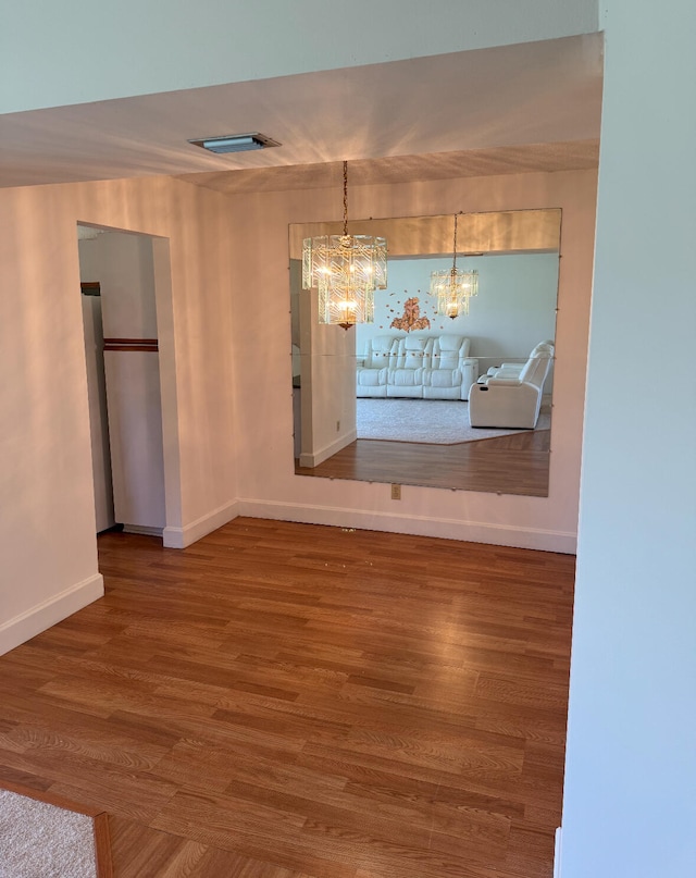 unfurnished dining area with wood-type flooring and an inviting chandelier