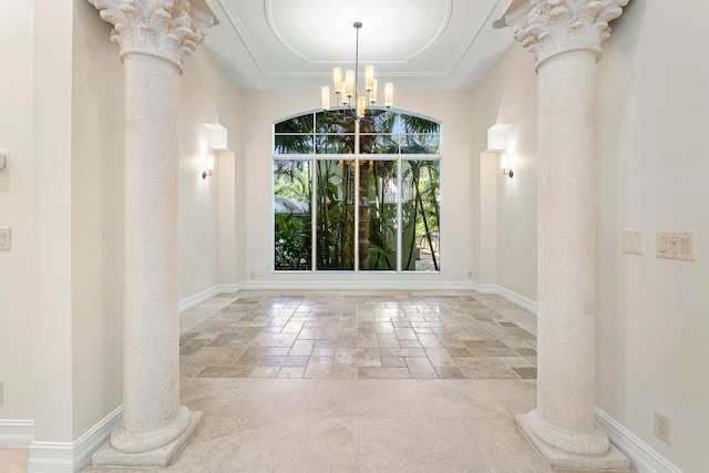 unfurnished dining area featuring a raised ceiling, ornate columns, and an inviting chandelier