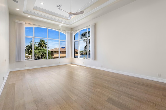 spare room with a raised ceiling, crown molding, ceiling fan, and light hardwood / wood-style floors