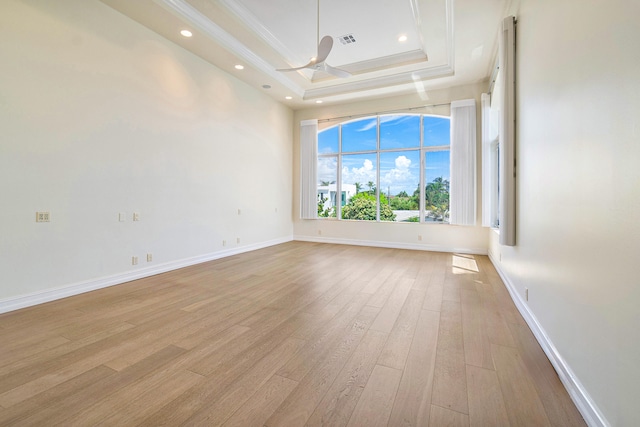 spare room with ceiling fan, crown molding, a tray ceiling, and light hardwood / wood-style flooring