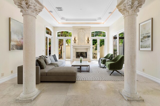 unfurnished living room with a raised ceiling, french doors, ornamental molding, and decorative columns