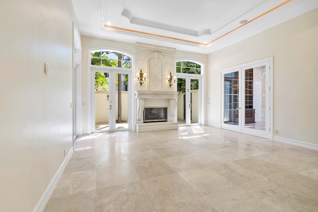 unfurnished living room with a tray ceiling, crown molding, and french doors