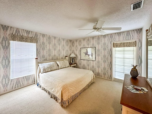 carpeted bedroom featuring a textured ceiling and ceiling fan