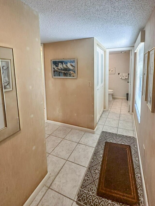 corridor featuring light tile patterned flooring and a textured ceiling