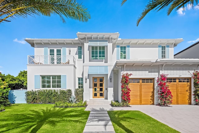 view of front facade featuring french doors, a balcony, a garage, and a front lawn