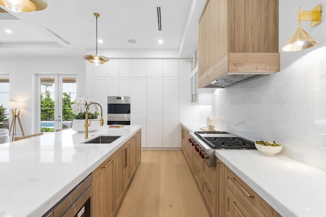 kitchen featuring pendant lighting, appliances with stainless steel finishes, white cabinetry, sink, and backsplash