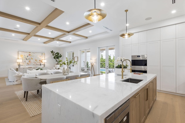 kitchen with light stone counters, pendant lighting, a large island, and coffered ceiling