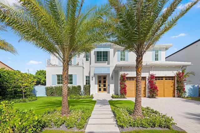 view of front facade with a front yard, french doors, a balcony, and a garage