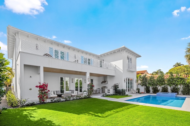 back of property with a fenced in pool, a balcony, a lawn, and a patio area