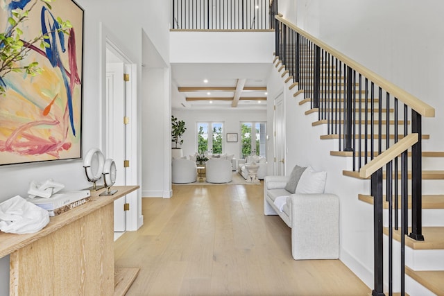 entrance foyer with coffered ceiling, beam ceiling, french doors, and light wood-type flooring